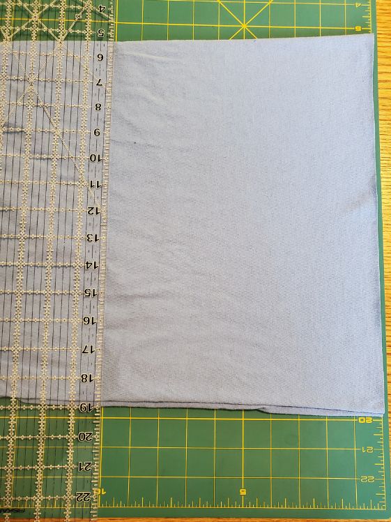 A t-shirt laid out on a cutting mat with a clear ruler at the 10 inch mark.