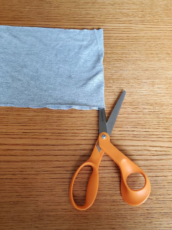 A scissors showing to cut the tshirt to make it one long strip.