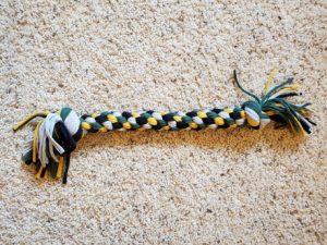 DIY t-shirt tug toy made from green, yellow, black, and gray t-shirts.