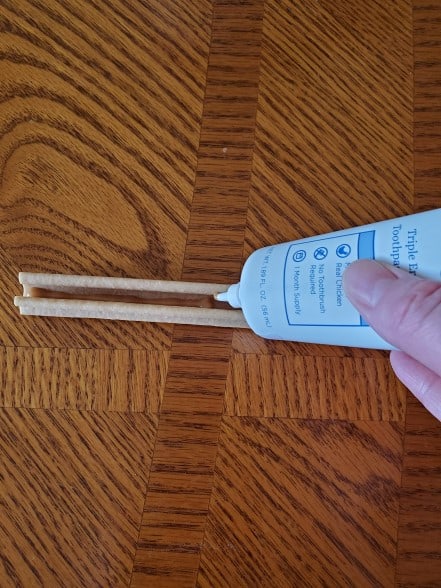 A dental chew with dog toothpaste being spread on it.