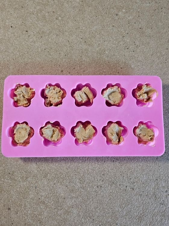 Dollops of the peanut butter yogurt mixture in paw shaped silicone molds.