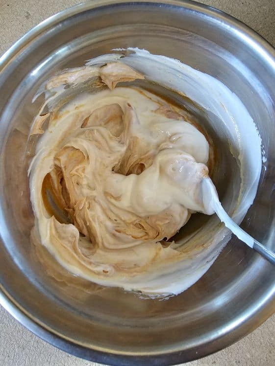 Greek yogurt and peanut butter being mixed in a bowl.
