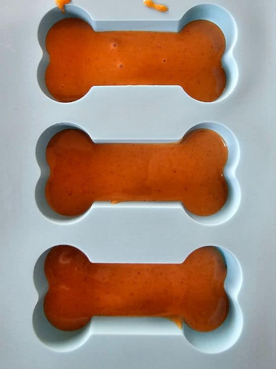 Melted peanut butter in a bone shaped silicone mold.