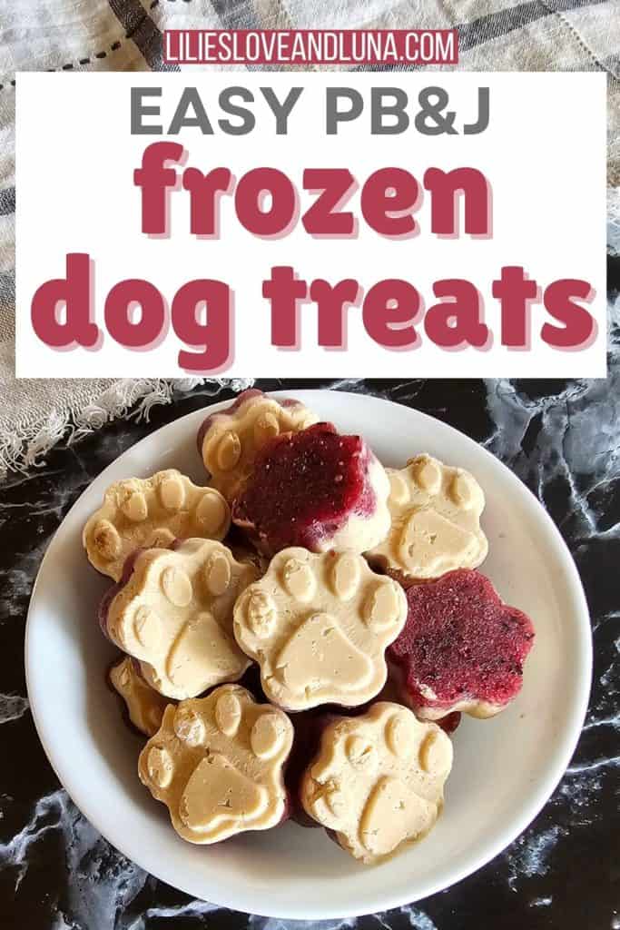 A bowl containing various frozen dog treats shaped like paws, made from peanut butter and jelly, sits on a marble surface.