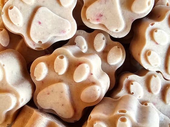Close up of paw shaped strawberry banana frozen dog treats.