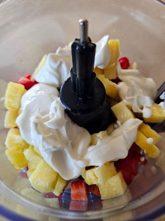 Strawberries, pineapple, and Greek yogurt in a food processor.