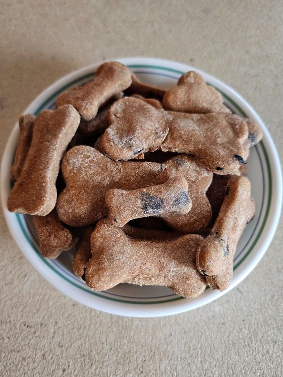 Bone shaped apple blueberry dog treats in a bowl.