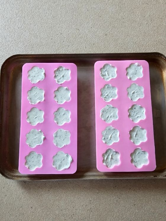 Paw shaped molds filled with the mint dog treat mixture.
