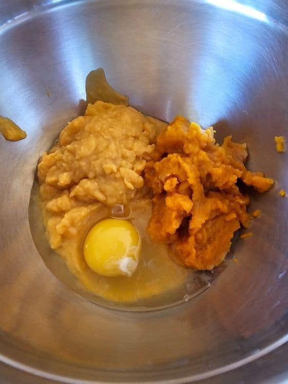 Sweet potato puree, pumpkin puree, and an egg in a mixing bowl.
