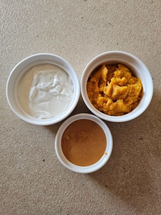Plain Greek yogurt, sweet potato puree, and peanut butter in individual white bowls.