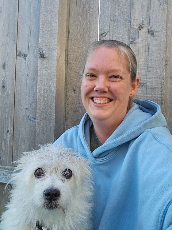 A mixed breed Alaskan Eskimo Dog next to a woman in a blue hoodie.