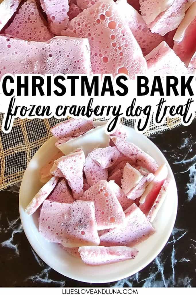 A bowl of frozen cranberry dog treats, labeled as "Christmas Bark," is displayed on a marble surface, showcasing a colorful assortment of treat pieces ideal for holiday gifting to pets.