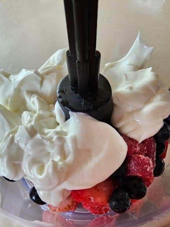 Greek yogurt, strawberries, and blueberries in a food processor.