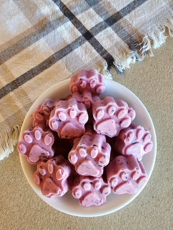 Paw shaped berry ice cream in a white bowl next to a linen towel.