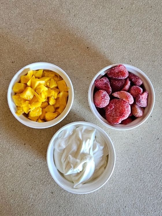Mango, strawberries, and Greek yogurt in individual white bowls.