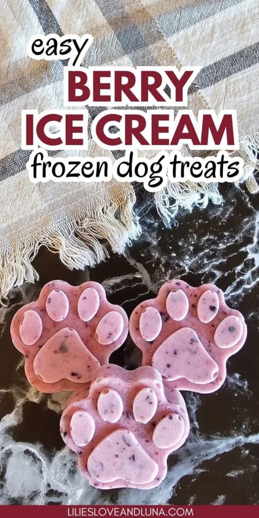 Three paw-shaped frozen dog treats in shades of pink are displayed on a dark surface, alongside a textured cloth, suggesting a recipe for easy berry ice cream dog treats.