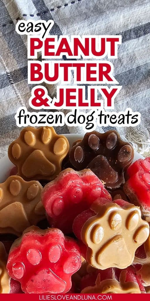 A bowl of frozen dog treats shaped like paw prints, featuring a mix of peanut butter and jelly flavors, sits on a textured cloth background.