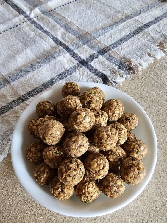 A bowl of zucchini banana balls next to a linen towel.