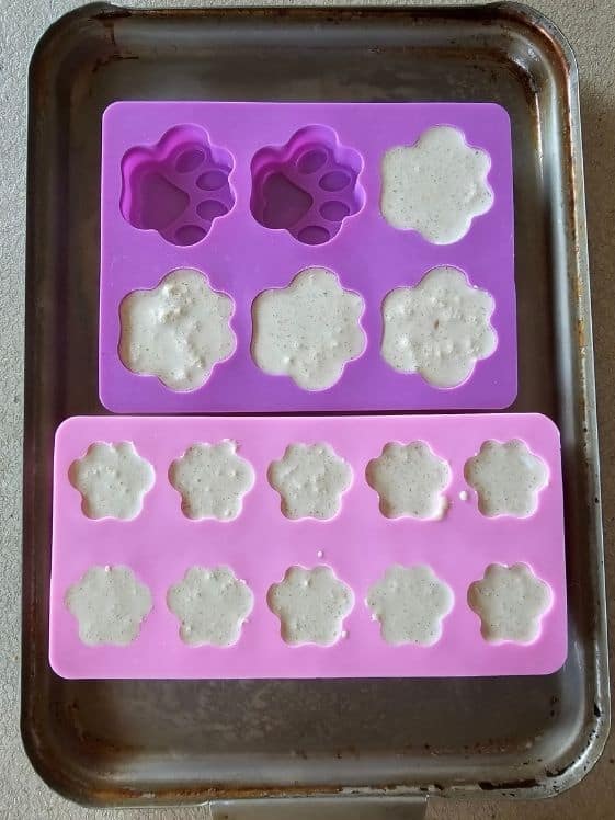 Paw shaped molds filled with the treat mixture.